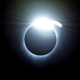 A bright flash of white appears at the top of a black circle, showing a solar eclipse. It appears like the diamond on top of a ring.