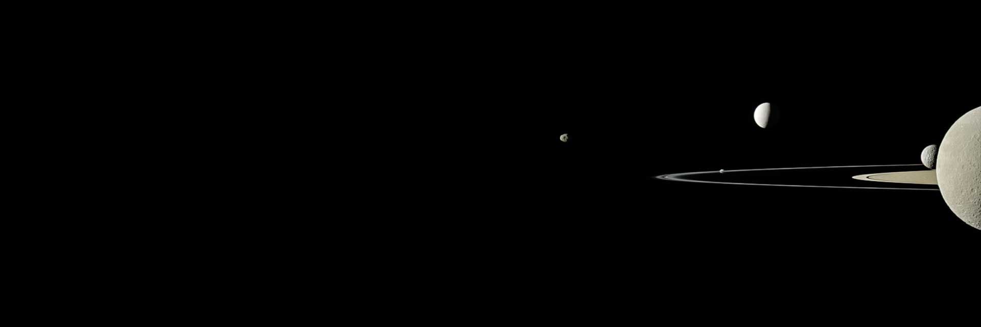 Saturn, some of its rings and five moons against the darkness of space