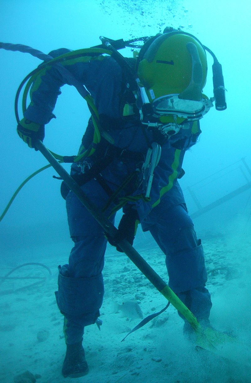 A SCUBA diver practices sample collection underwater, on the seafloor.