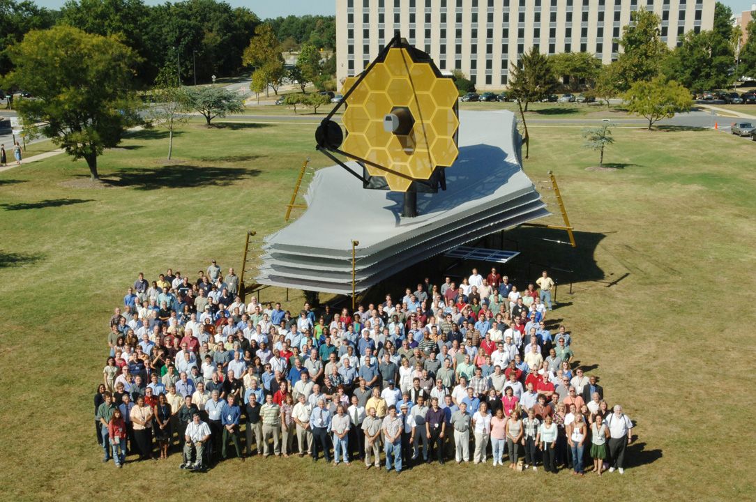 Dozens of people grouped together in front of the full scale model of Webb.