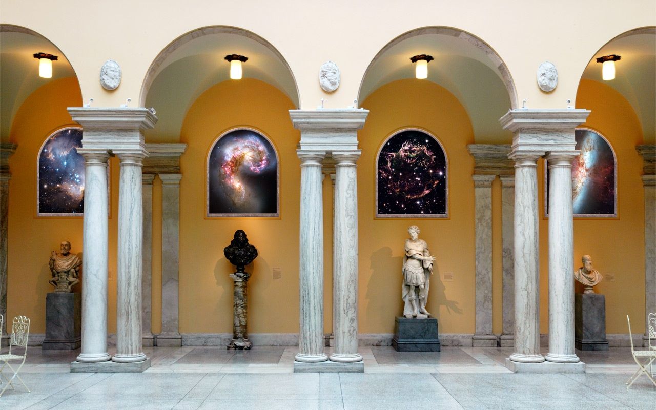 Hubble images are mounted on the wall over sculptures and between classical pillars at the Walters Art Musuem.