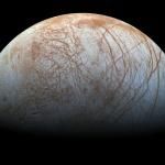 A semi-circular view of Europa, with its light blue and brown surface marked with brown lines.
