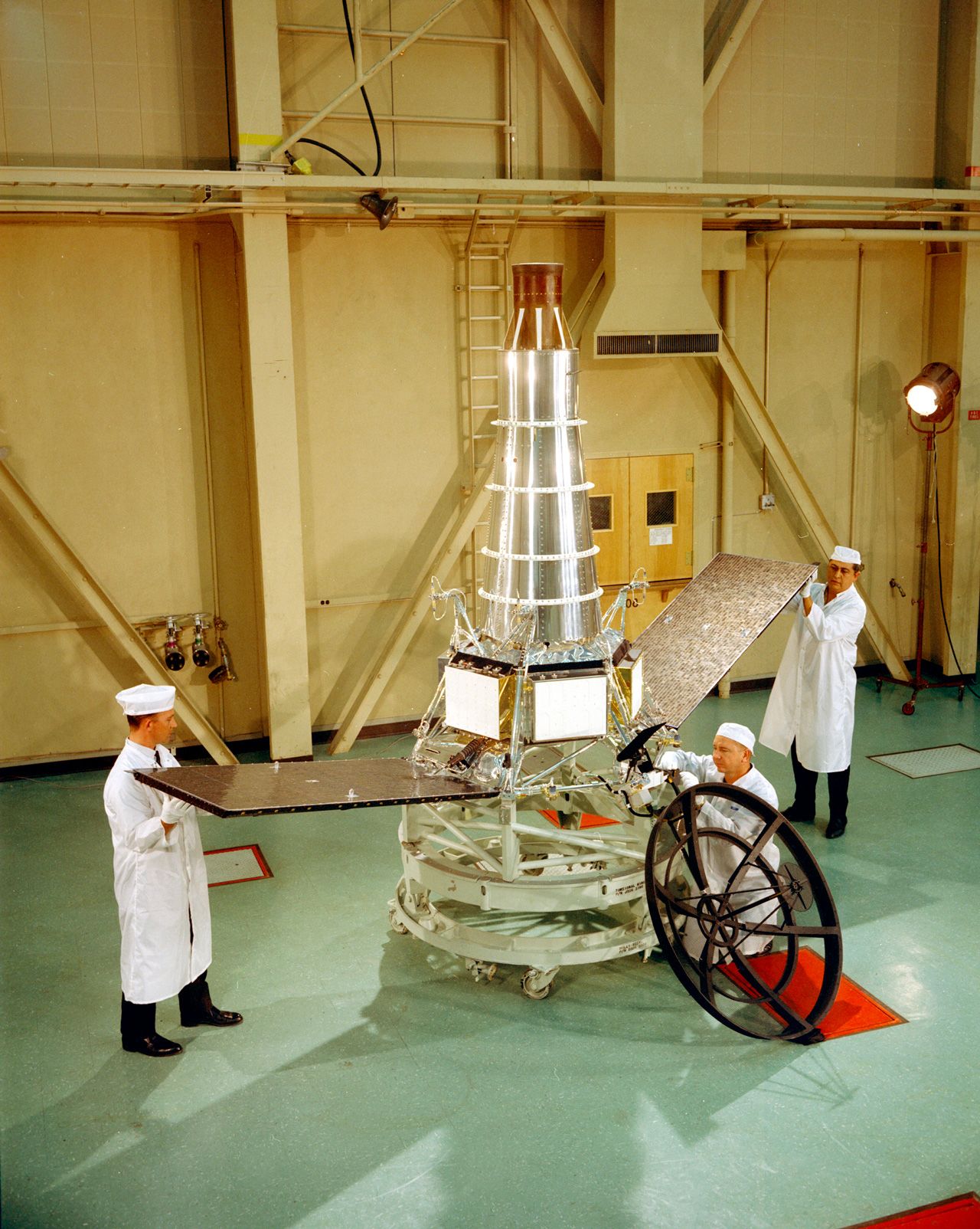 Three engineers working on a spacecraft.