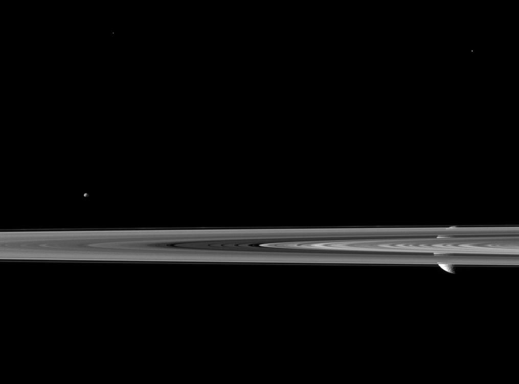 Saturn's second largest moon Rhea pops in and out of view behind the planet's rings in this image from the Cassini spacecraft, which includes the smaller moon Epimetheus.
