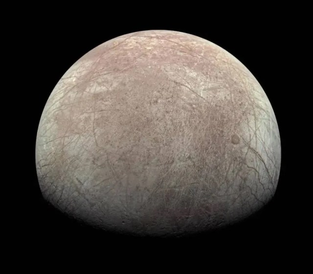 The pale gray of Europa is seen against the blackness of space.