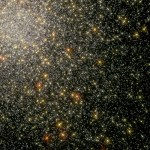 A mass of yellow and white stars fill the upper-left corner and taper off toward the lower-right corner. Reddish-orang stars dot the scene, all on a black background.