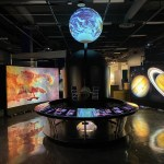 A 3-foot sphere is illuminatedabove the centerpiece station with the earth projected onto it.