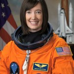 Photo of astronaut Megan McArthur in her orange spacesuit. American flag is behind her.