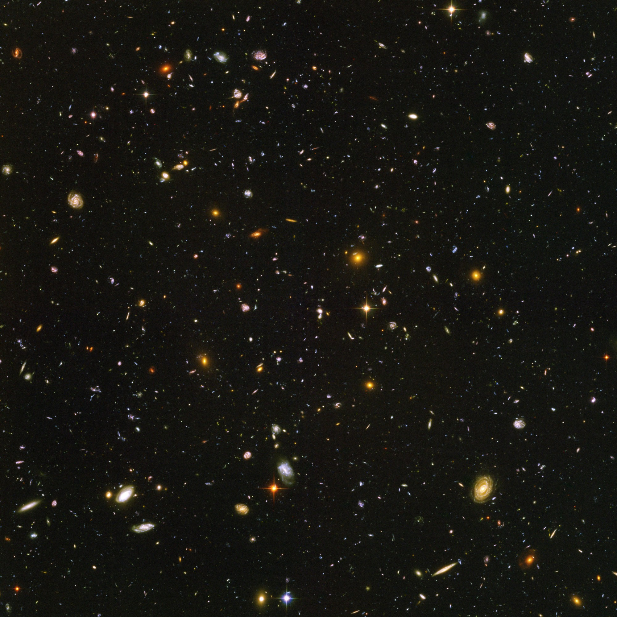 Field is filled with galaxies in colors of white, yellow, blue-white, and red; all on a black background.