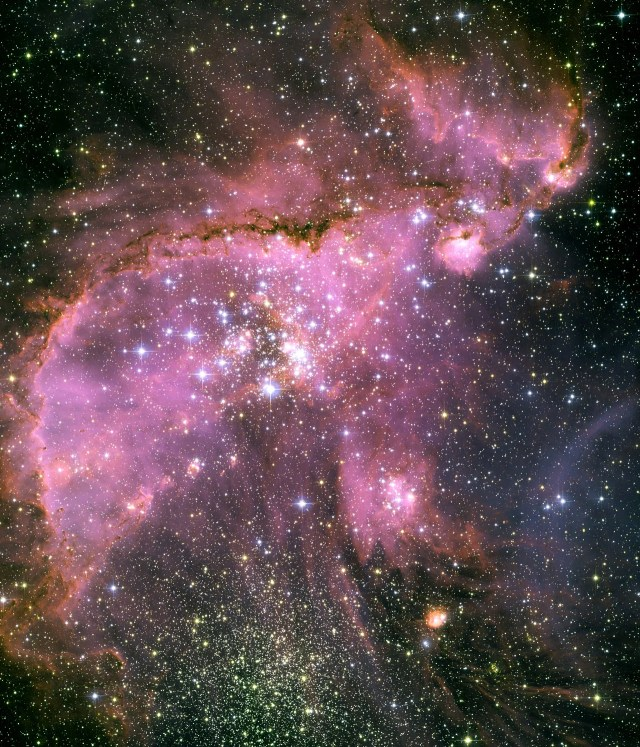 Upper left half of the image is filled with bright-pink clouds dotted with stars. A lobe of the pink clouds extends below the cloud toward the lower-right corner. Lower right half of the image is black and dotted with stars.