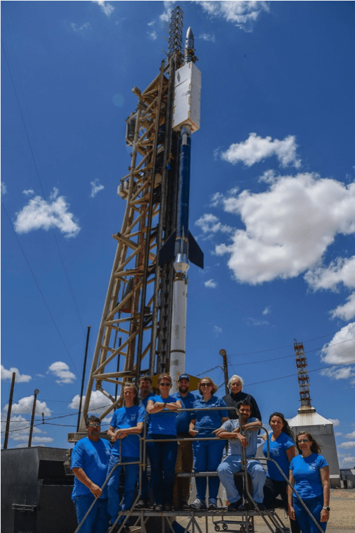 Photo of 10 people in blue tshirts standing in front of launch scaffolding.