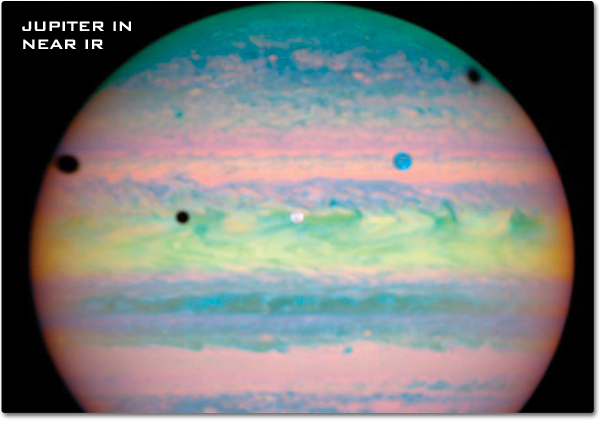 This false-color Hubble image of Jupiter shows pastel pinks, greens, yellows and blues stretched in lines across the gas planet.