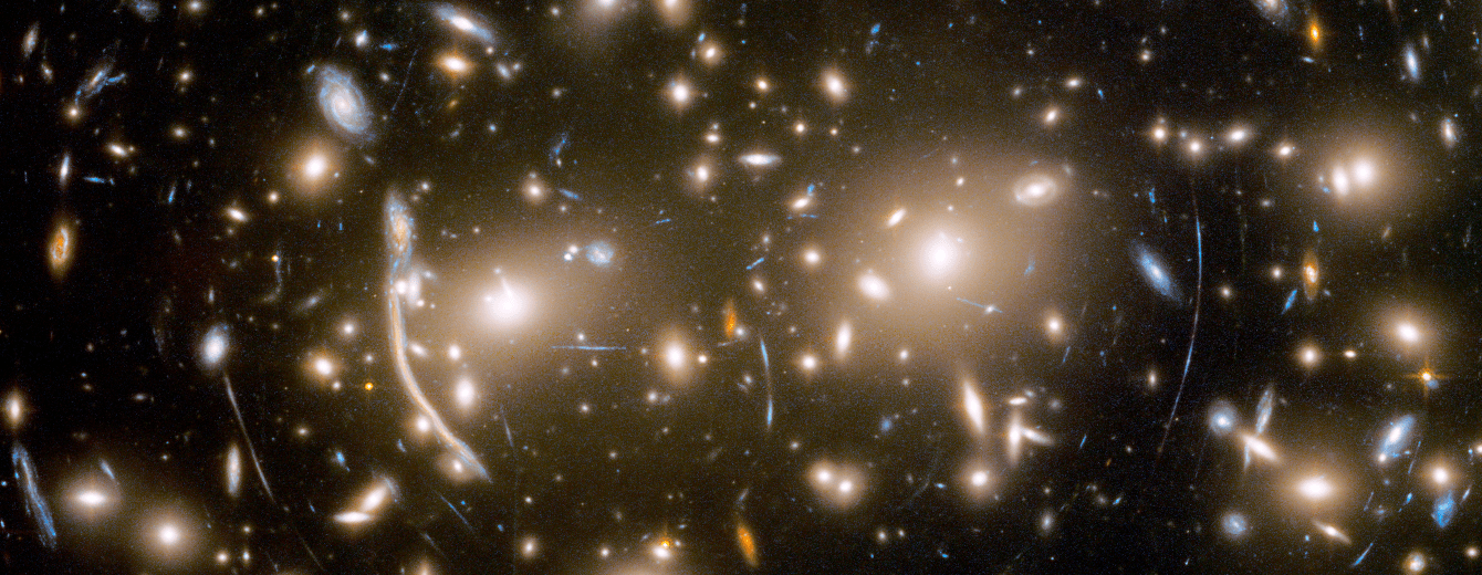 Countless galaxies in orange, white, light blue, and yellow fill the screen against a black background. Faint arcs appear to curve around the image's center.