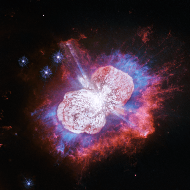 This Hubble Space Telescope image of the giant, petulant star Eta Carinae is yielding new surprises. Telescopes such as Hubble have monitored the super-massive star for more than two decades. The star, the largest member of a double-star system, has been prone to violent outbursts, including an episode in the 1840s during which ejected material formed the bipolar bubbles seen here. Now, using Hubble's Wide Field Camera 3 to probe the nebula in ultraviolet light, astronomers have uncovered the glow of magnesium embedded in warm gas (shown in blue) in places they had not seen it before. The luminous magnesium resides in the space between the dusty bipolar bubbles and the outer shock-heated nitrogen-rich filaments (shown in red). The streaks visible in the blue region outside the lower-left lobe are a striking feature in the image. These streaks are created when the star's light rays poke through the dust clumps scattered along the bubble's surface. Wherever the ultraviolet light strikes the dense dust, it leaves a long, thin shadow that extends beyond the lobe into the surrounding gas. Eta Carinae resides 7,500 light-years away.