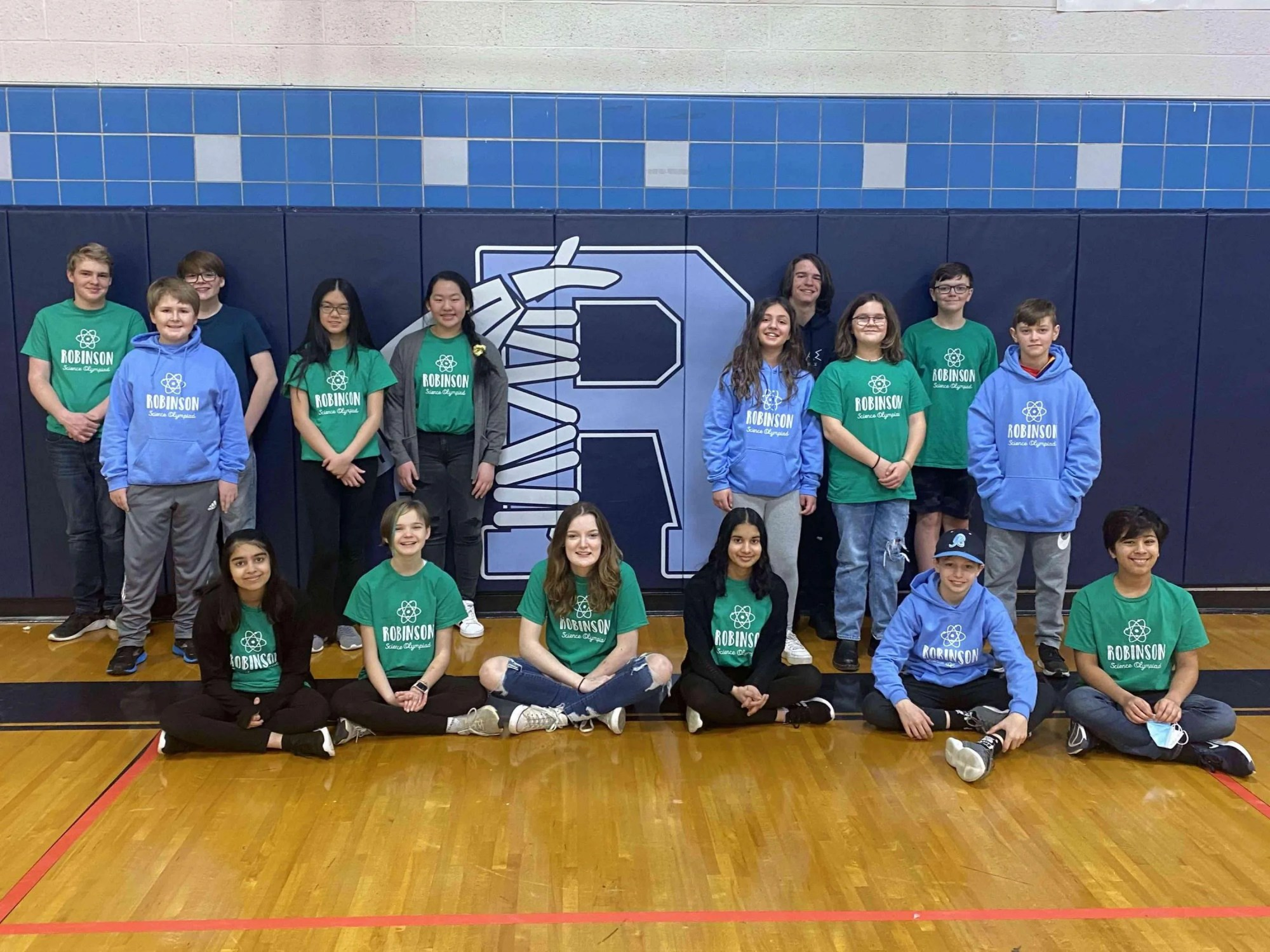 Photo of smiling Division B team from Ross N. Robinson Middle, Tennessee of 10 youths standing and 6 youths sitting in green and light blue Robinson Science Olympiad shirts.