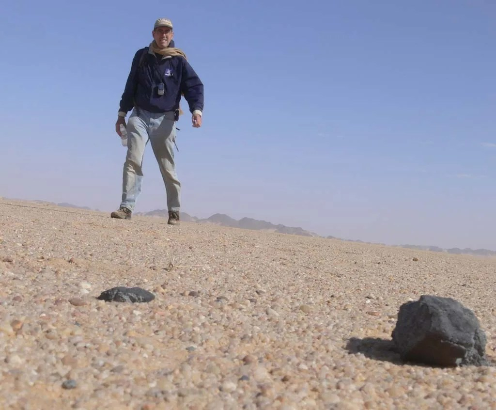 man and meteorite rock on ground