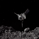 An artistic visualization of the OSIRIS-REx spacecraft hovering above the surface of Asteroid Bennu. The spacecraft is silver, shiny with two wings on the top and a long extension from the bottom.