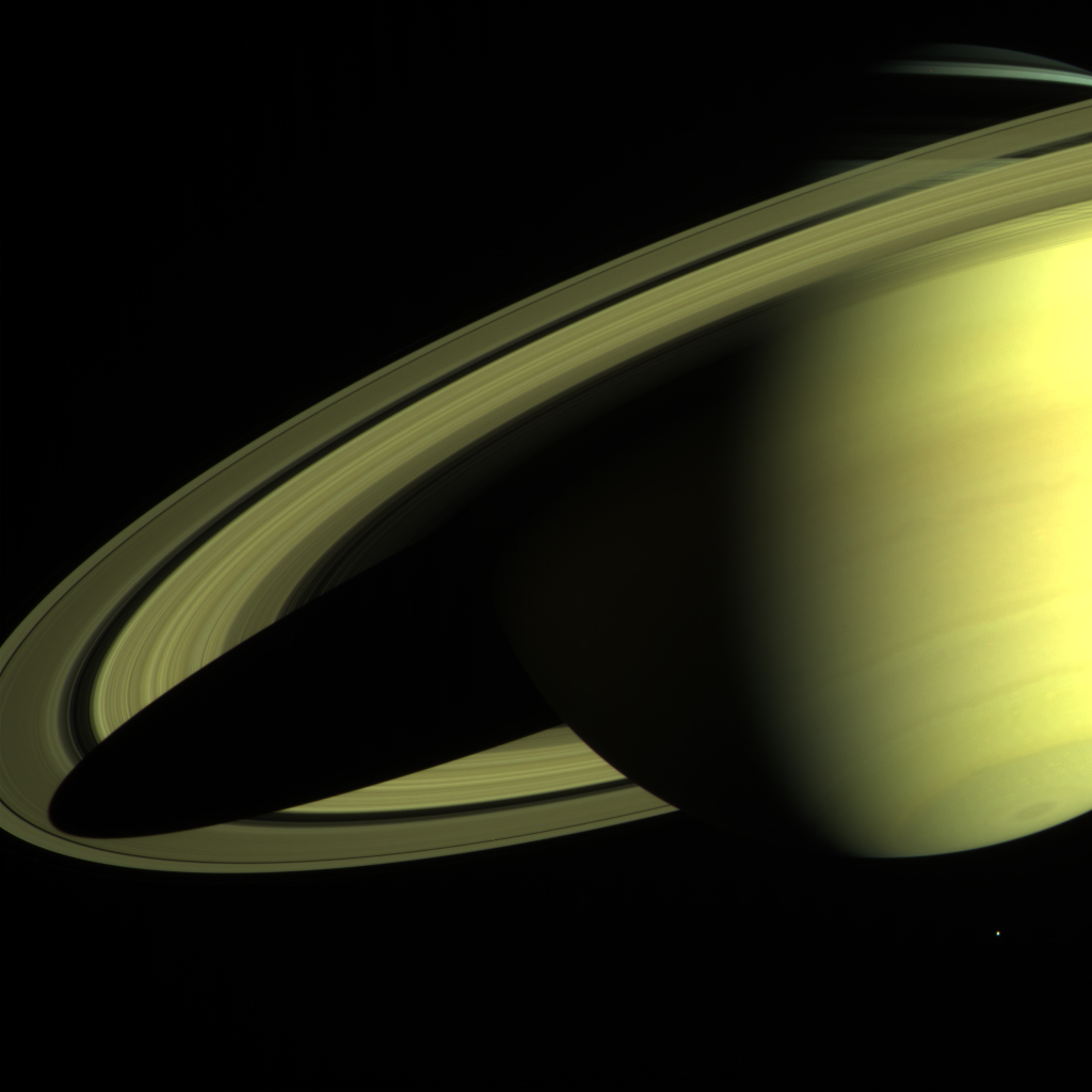 Bright yellow Saturn. We see two-thirds of the planet. The left side of the image showcases the rings. The planet is right side of the image and is casting its shadow on the rings.