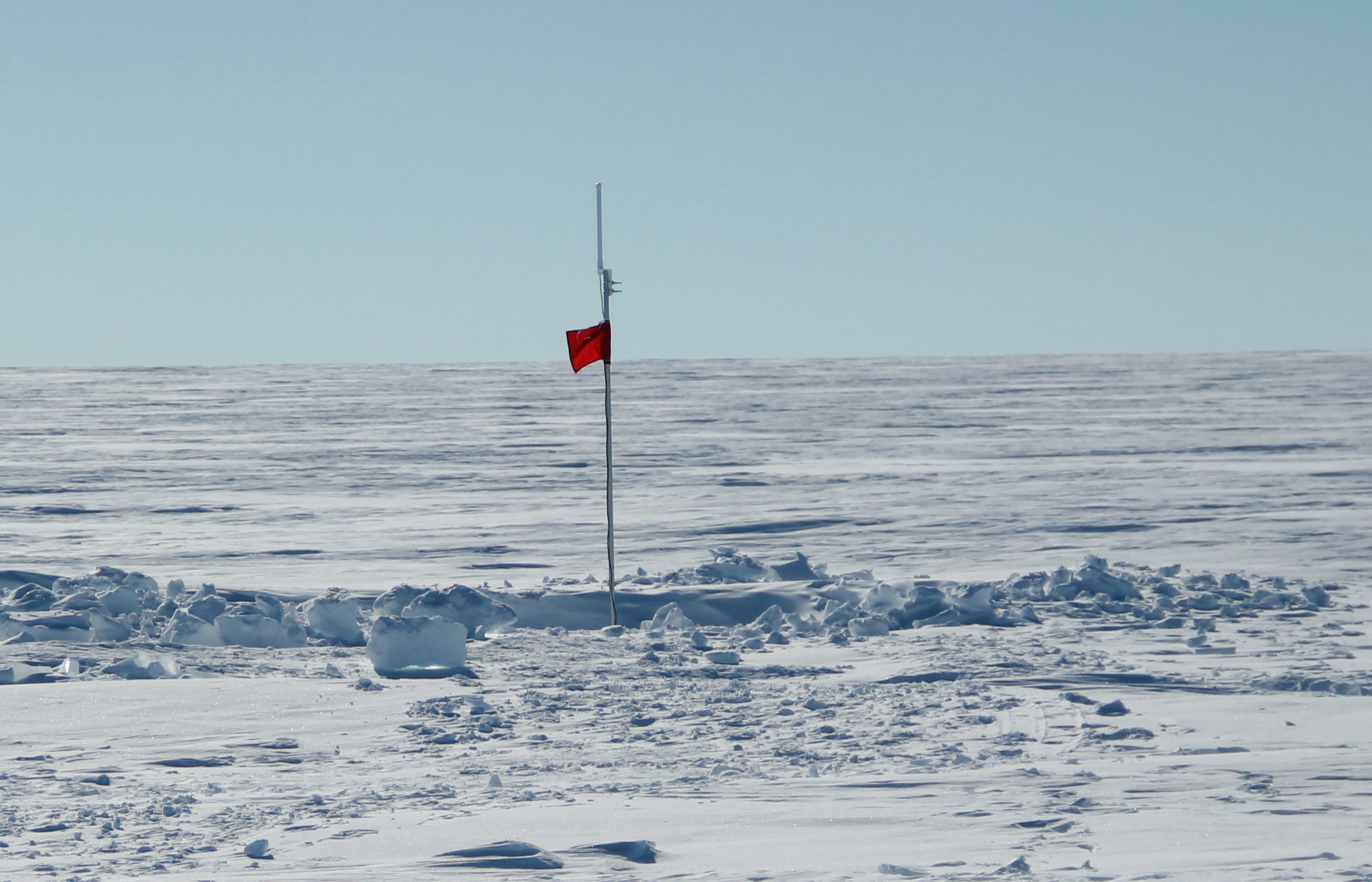 After backfilling the snow pit, the only evidence at the surface of the temperature strings is the top of the pole with the ARGOS antenna and a red flag!