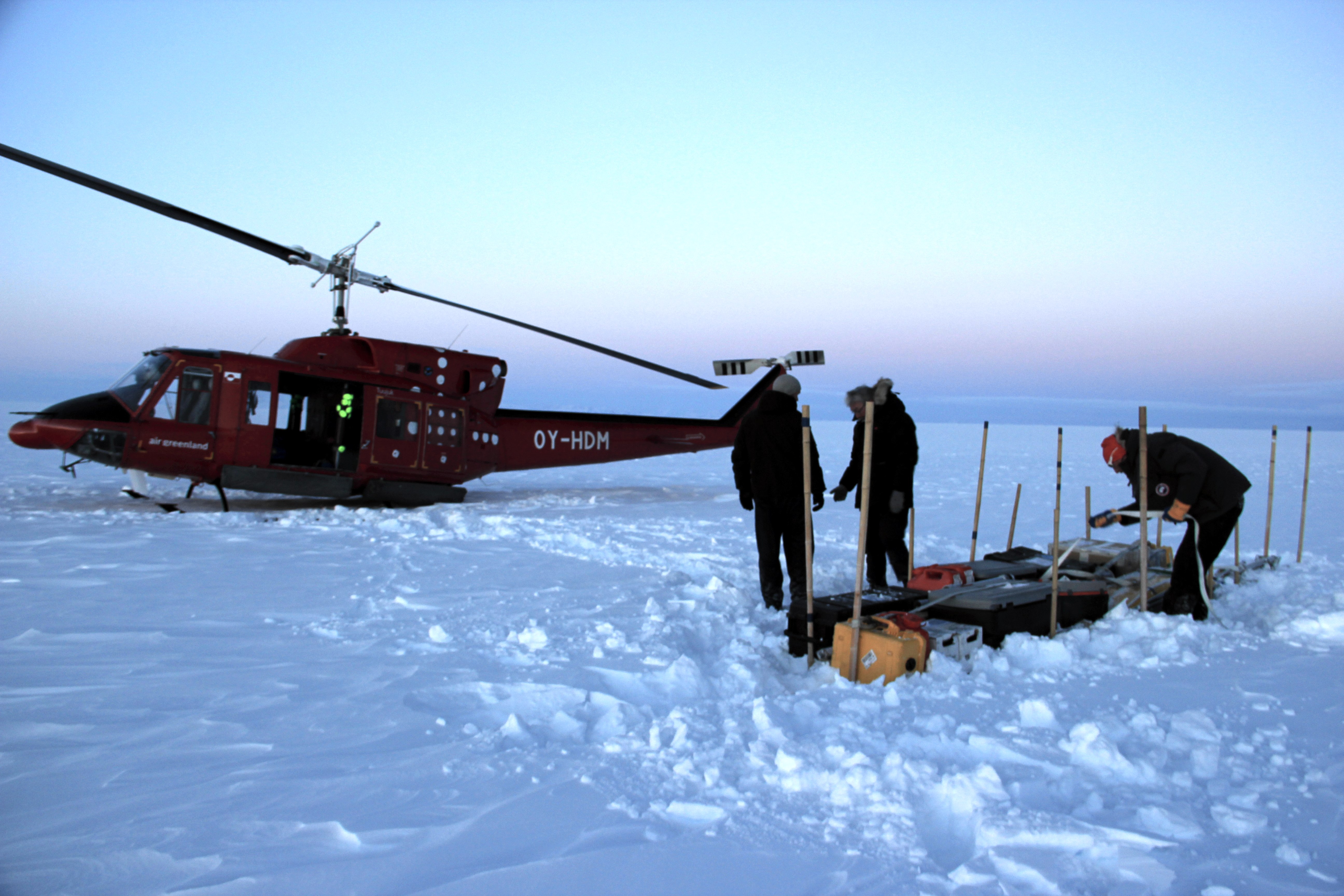 Our cargo line on the ice sheet, near the temperature probe and Argos antenna we left behind in 2013. I'm finishing up by deploying a second cargo strap across the line and through the boxes handles. (Credit: Clément Miège)