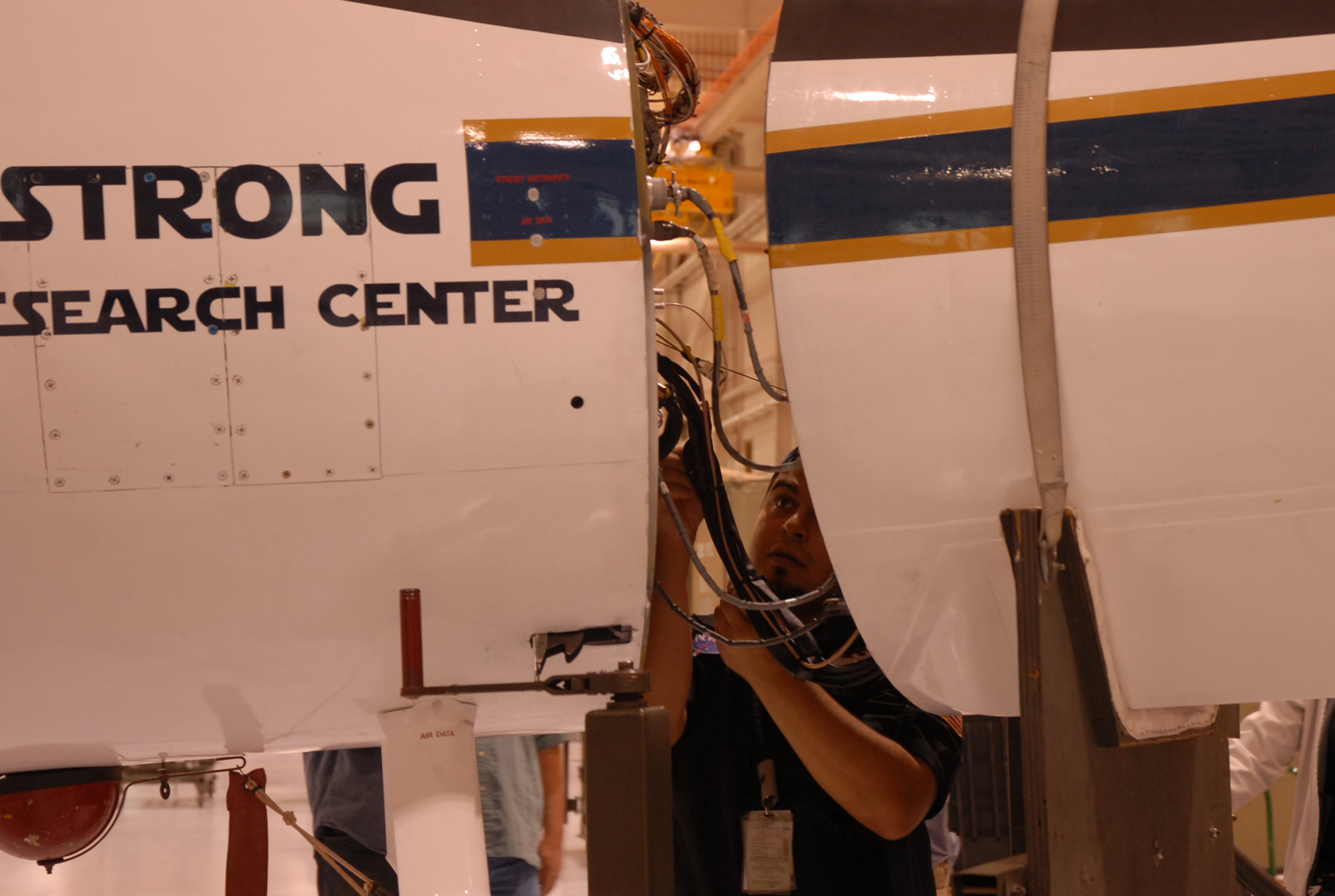 Luis Rios, with NASA's ER-2 crew, checks the connections between the MABEL instrument and the aircraft. (Credit: Kate Ramsayer/NASA)