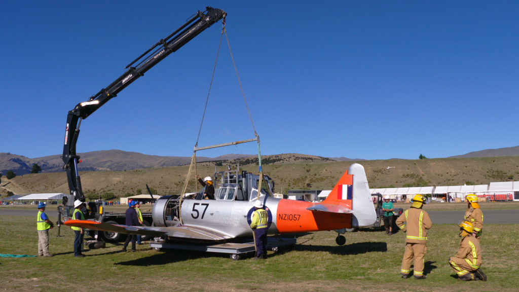 Technicians use a crane to lift a small aircraft.