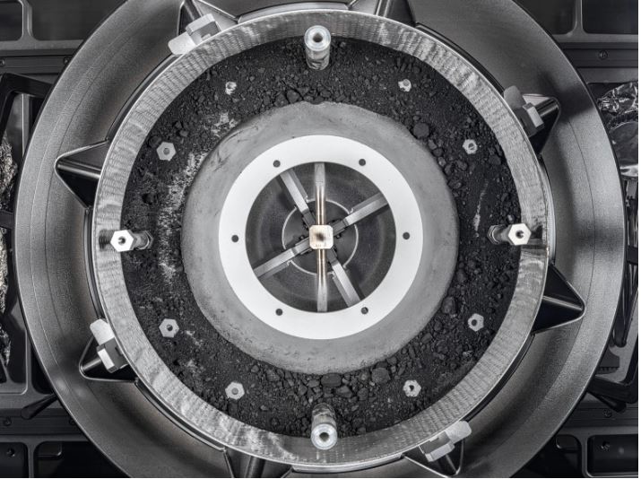 The circular sample head containing a ring of dark gray asteroid material around the outer edge
