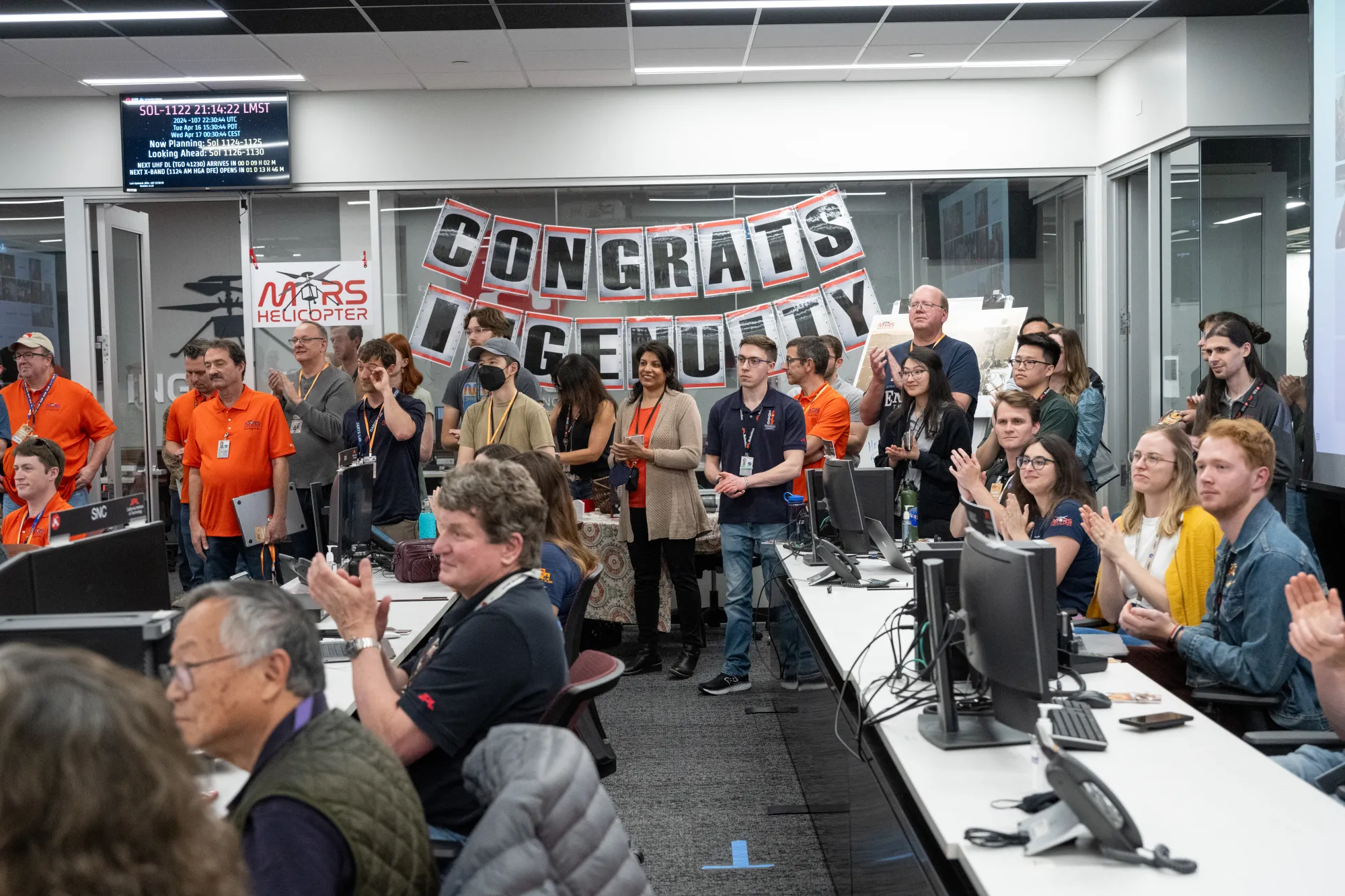 People gathered in control room with "Congrats Ingenuity" banner on back wall