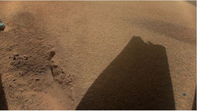 shadow of rotor blade with damage to tip against Mars surface
