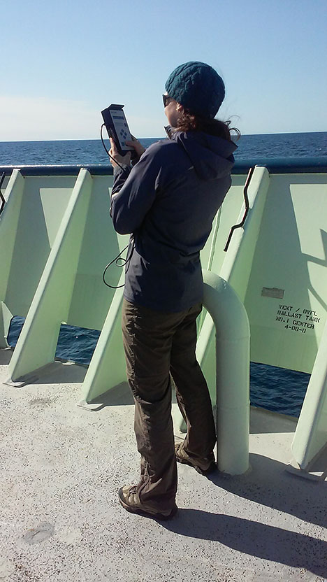 Cleo Davis measuring the amount of aerosols between the RV Atlantis and the sun, using Microtops.  Photo: Kelsey McBeain