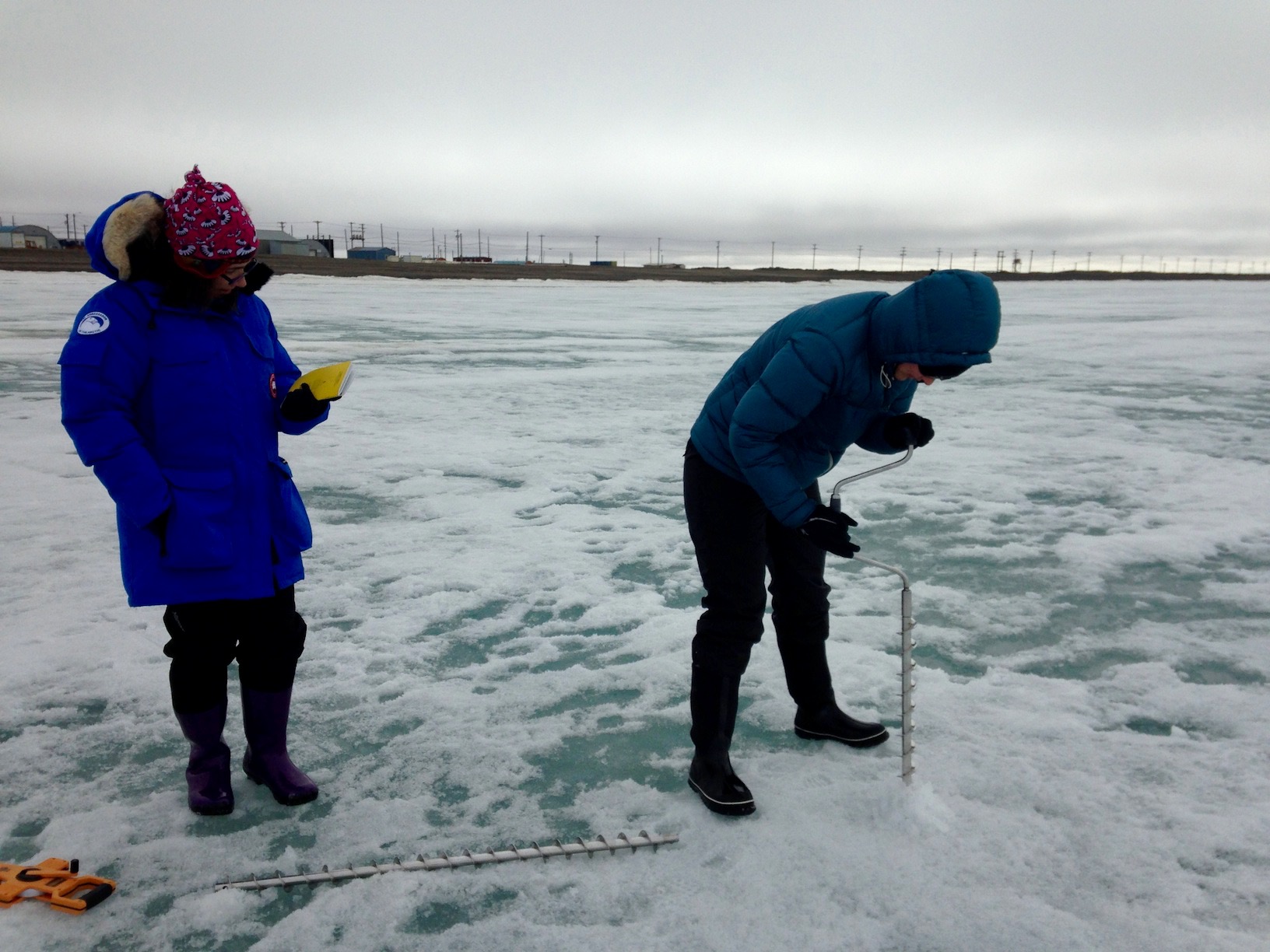 Two members of the Red team drilling with an ice auger.
