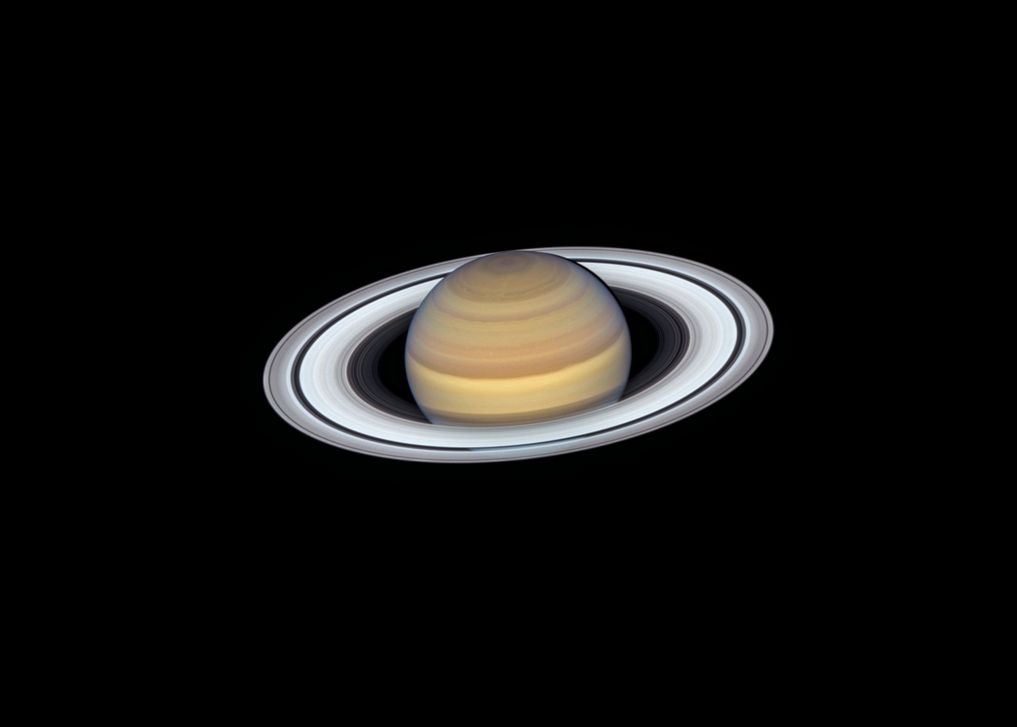 Saturn and its glowing rings in stark contrast against the blackness of space