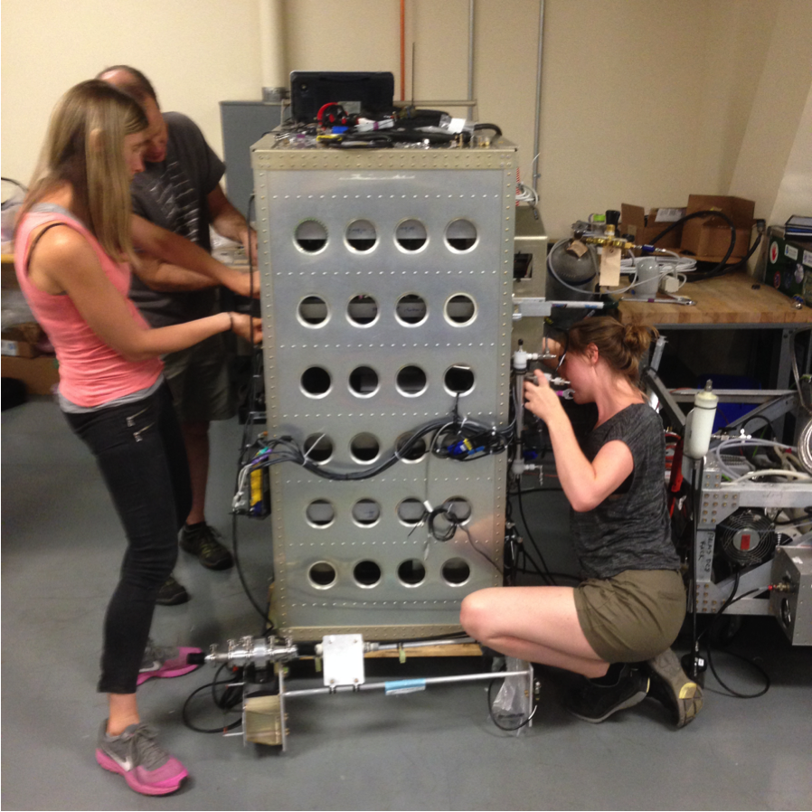 Assembling the instrument rack in the lab at NASA Armstrong. From left to right, Frank Erdesz, engineer with CIRES/NOAA, Charles Brock, Principal Investigator from NOAA, Agneiszka Kupc, research scientist with NOAA/University of Vienna, and Christina Williamson, research scientist with CIRES/NOAA. (Credit: Maximilian Dollner)