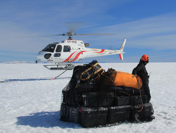 Nick (orange helmet) has the last sling load ready to go and is getting prepared to hook it on to the cable attached to the helicopter.