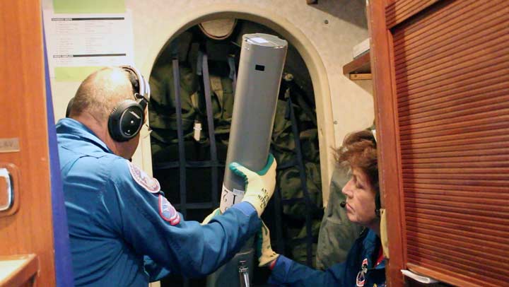 The two images above show flight Engineers Phil Vaughn and Terry Lee ready to drop an AXCTD through a hole in the bottom of the plane. 