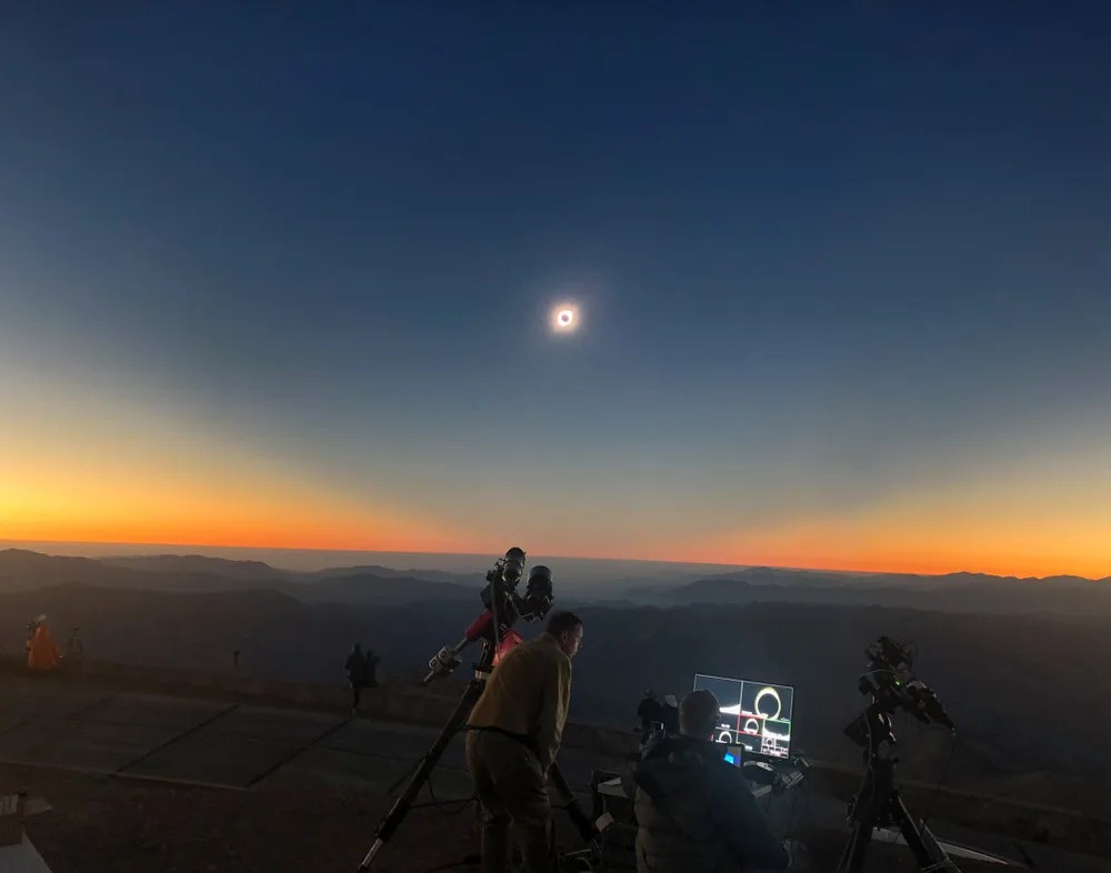 Image of the moon eclipsing the sun and the resulting 360 degree sunset on the horizon with the telescope and video production unit for the live broadcast in the foreground - Cerro Tololo International Observatory, Chile - July 2, 2019