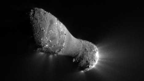 Closeup view of a peanut-shaped comet with sunlight reflecting off it
