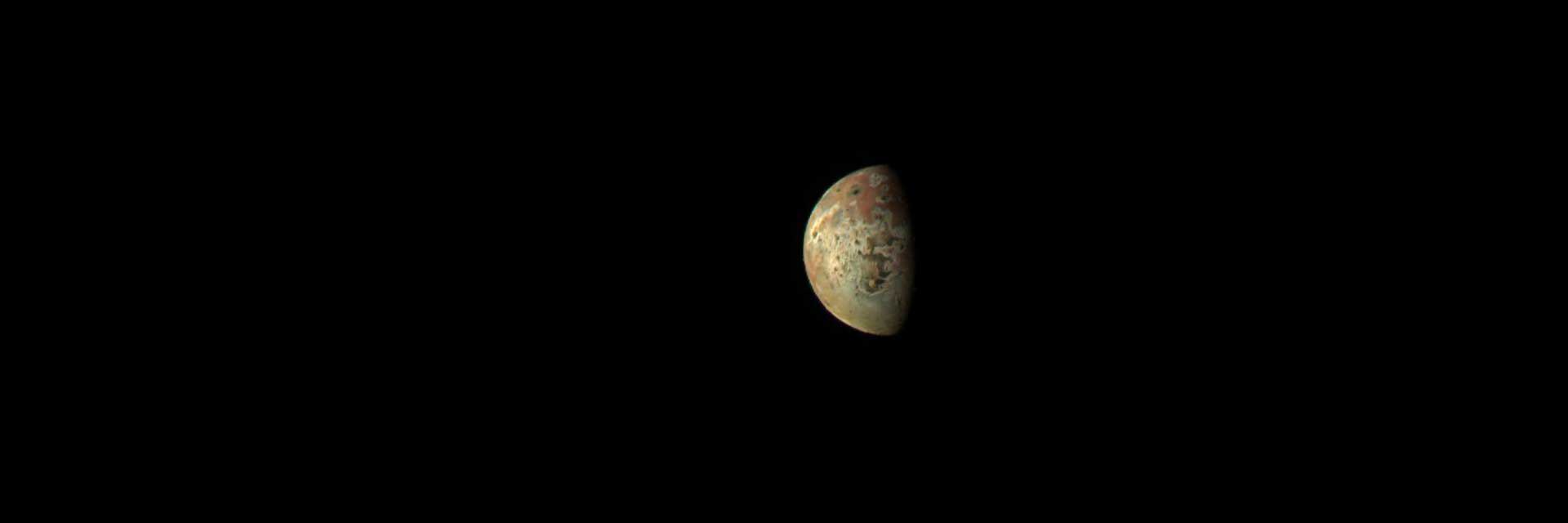 Orange and yellow moon Io is seen against the darkness of space.
