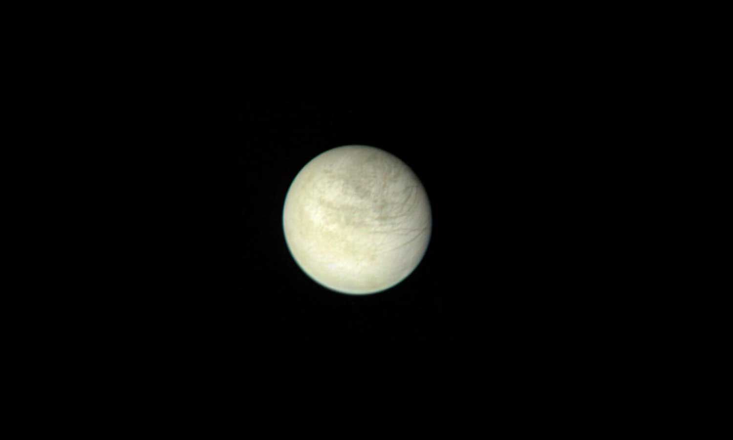 A yellowish-looking Europa against the blackness of space.