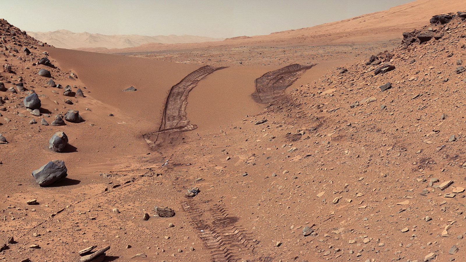Deep tire tracks are visible in the Martian sand where the Curiosity rover crossed over a dune on Mars.