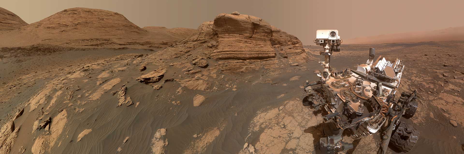 火星漫游者坐在火星的红土上，面对摄像机自拍