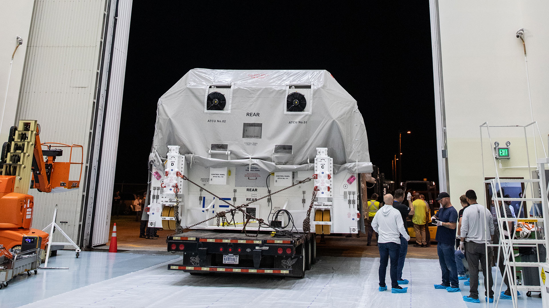 Europa Clipper is rolled into the Payload Hazardous Servicing Facility while workers stand nearby.