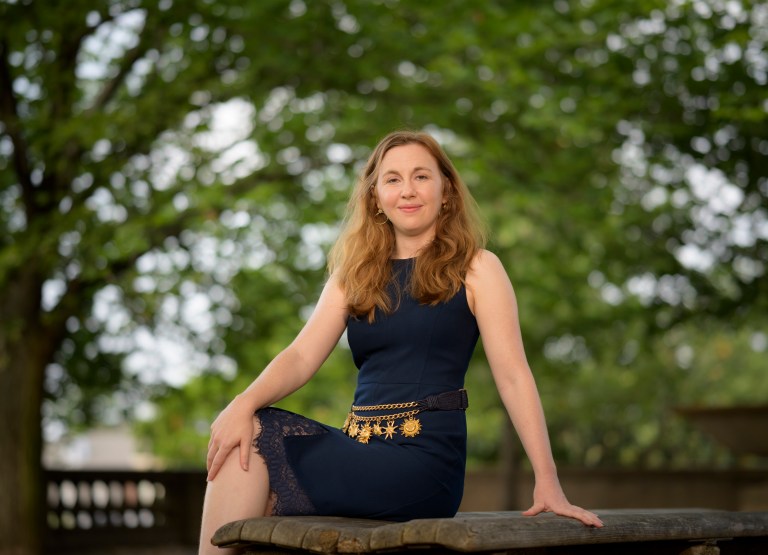 Elizabeth Landau sits for a formal portrait against a backdrop of trees.