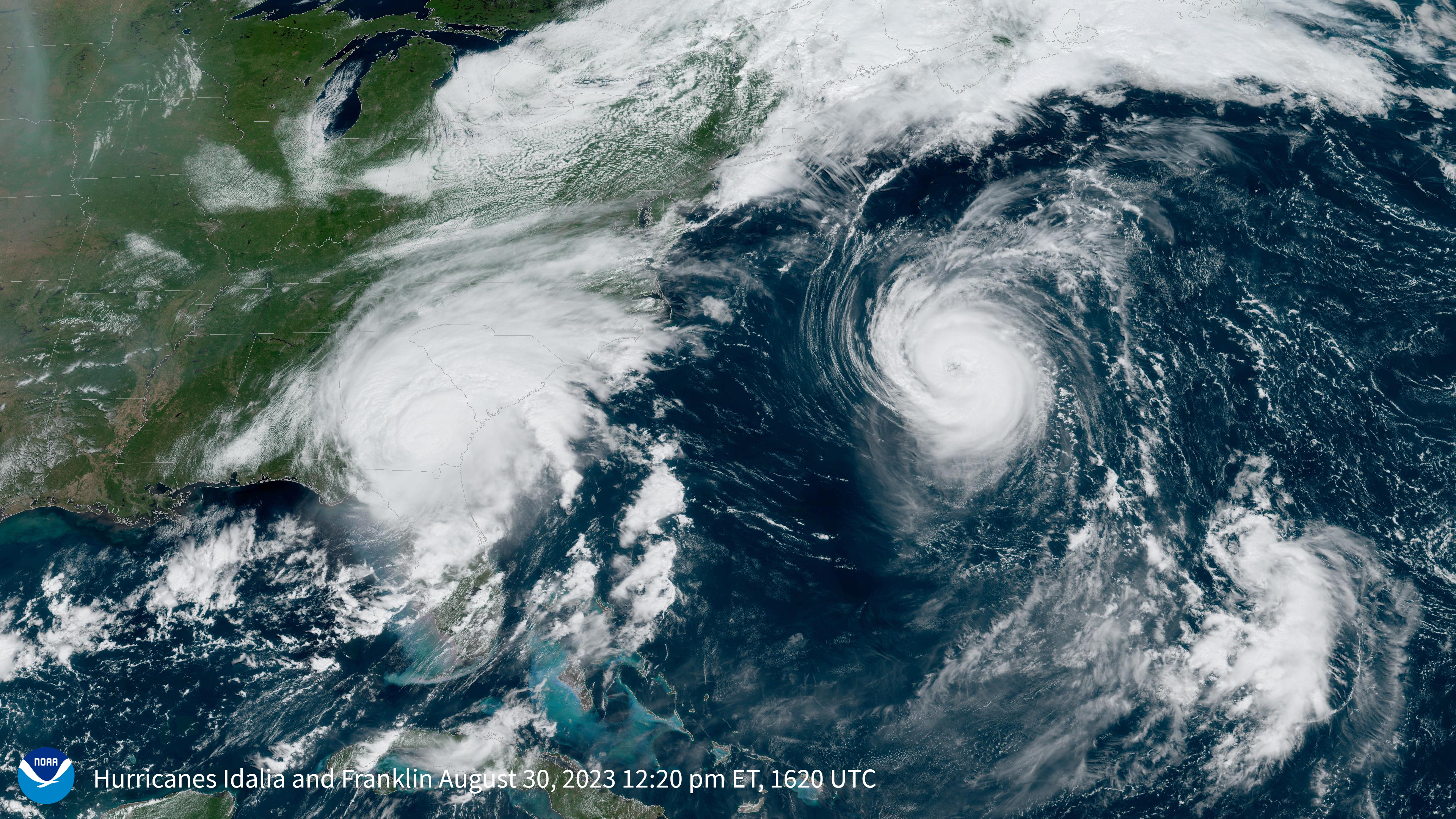 Satellite imagery showing the white clouds of two hurricanes against the blue ocean and green land of the U.S. East Coast