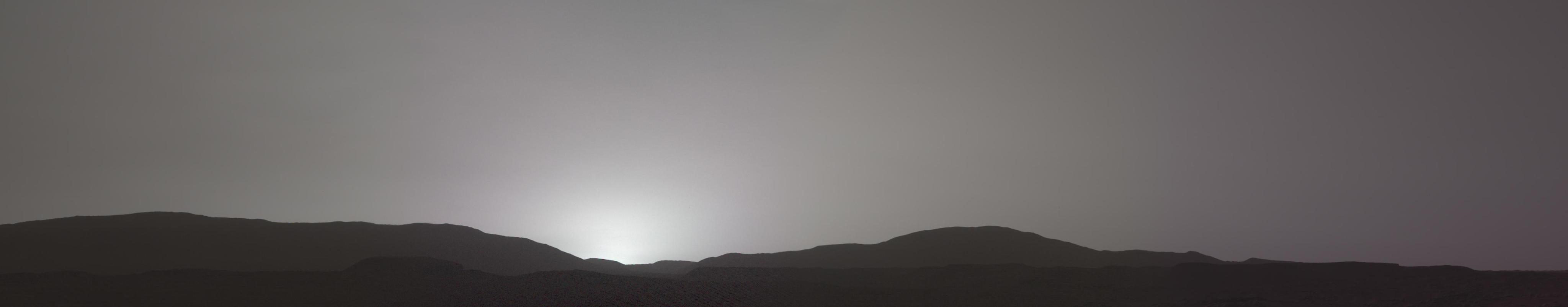 The sun sets behind hills on Mars.