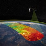 Above Earth, the International Space Station orbits. From one area toward the middle of the station, a transparent cone highlights a rainbow stripe of Earth's atmosphere.