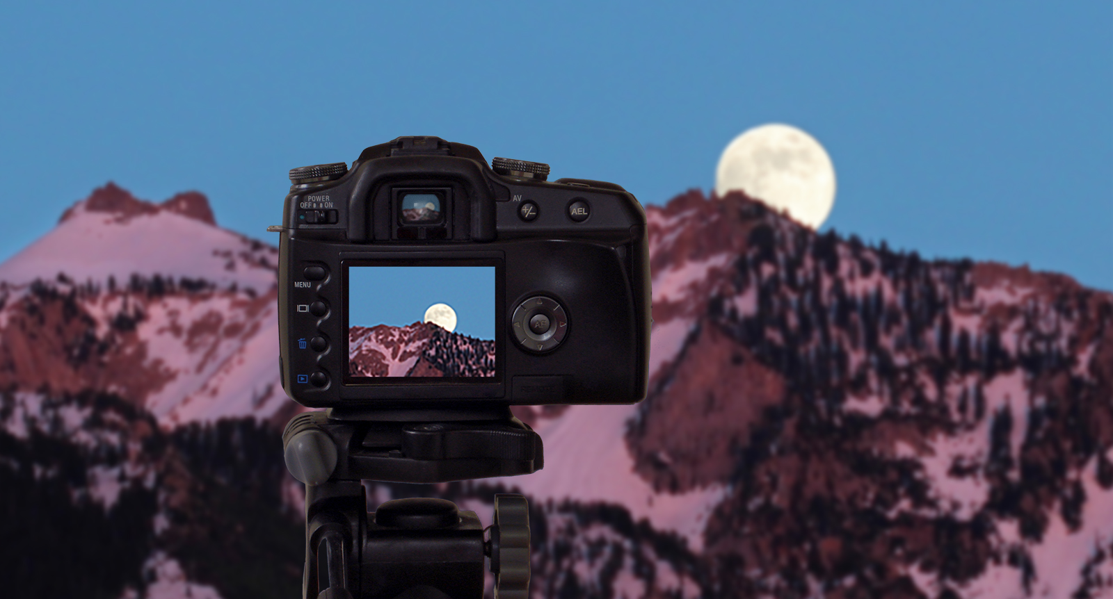 Composite of a camera pointing to a mountain landscape with the full Moon.