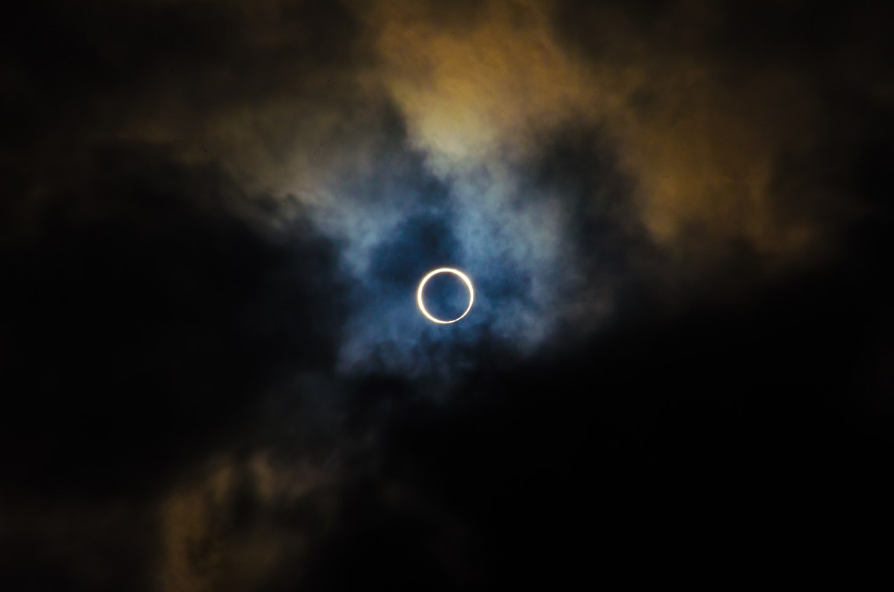 A total solar eclipse with clouds surrounding it.