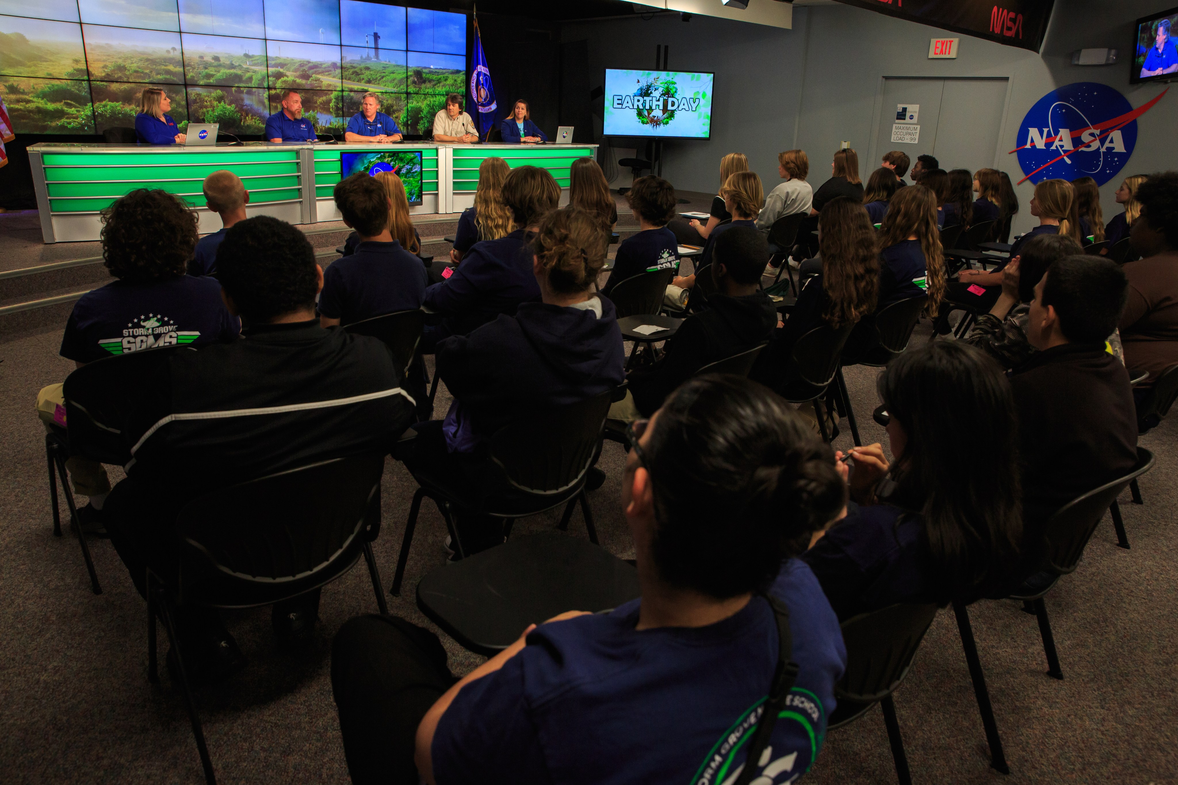 Students sit in front of a panel of speakers at the Kennedy Space Center.