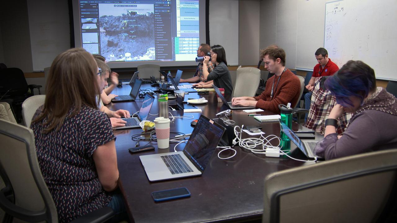 A group of people sitting around a conference table with their laptops out.